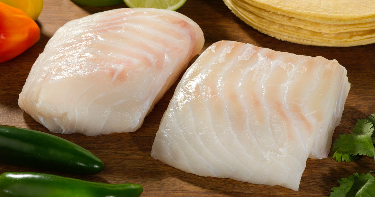 Cod Portions on Wood Cutting Board with Herbs and Peppers