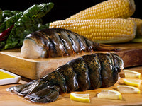 Jumbo Cold Water Lobster Tails on Wood Cutting Board with Lemon Slices