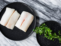 Black Cod Portions on Plate Next to Plate of Microgreens