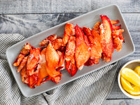 Cooked Lobster Meat in Serving Tray Next to a Bowl of Lemon Wedges