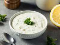 Fulton Fish Market Classic Tartar Sauce in a white bowl with spoons, lemon, and herbs