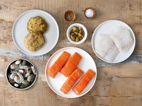 Starter Bundle with crab cakes, shrimp, salmon portions and cod portions on a wood table