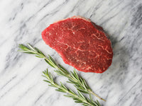 Raw Pat LaFrieda Prime Filet Mignon on Marble Surface with Rosemary Sprigs
