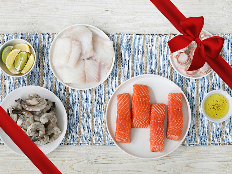 Shrimp, Bacon-Wrapped Scallops, Atlantic Salmon, and Atlantic Cod on Plates on Wood Table with Placemat and Gift Ribbon
