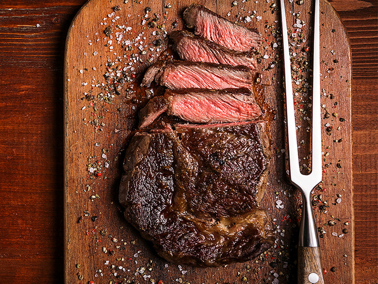 Cooked Japanese A5 Wagyu Ribeye Sliced on Wood Cutting Board with cooking fork and spices