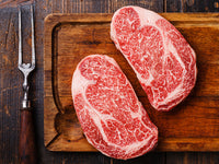 Raw Japanese A5 Wagyu Ribeye on Wood Cutting Board with cooking fork