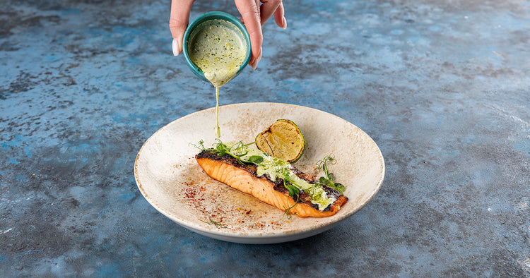 Sauce Being Poured Over Grilled Salmon on Plate