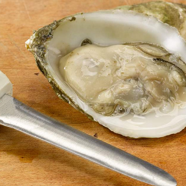 Freshly Shucked Oyster on Wooden Surface with Oyster Knife
