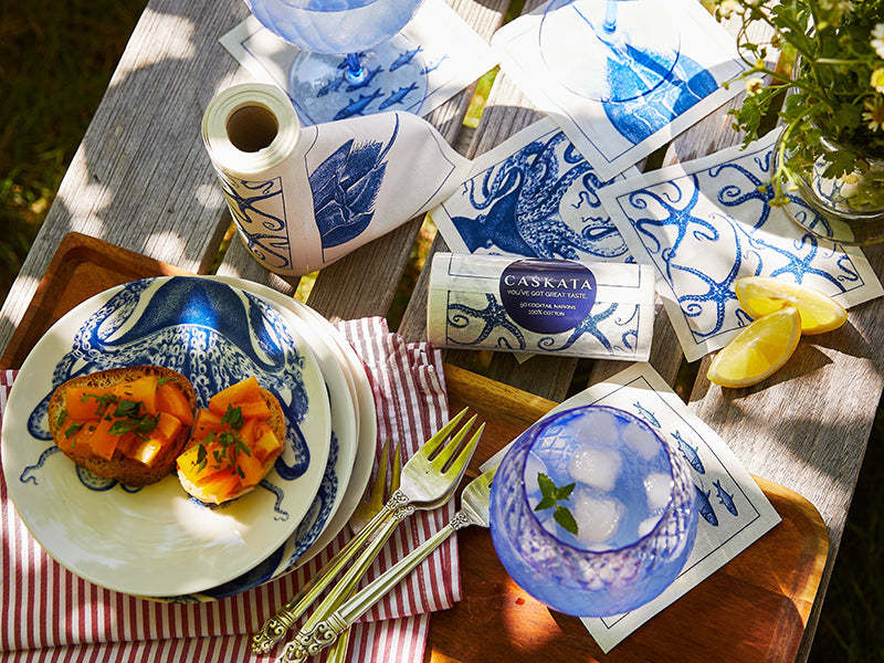 Coastal Cocktail Napkin Rolls on Wood Table with Appetizers and Drink