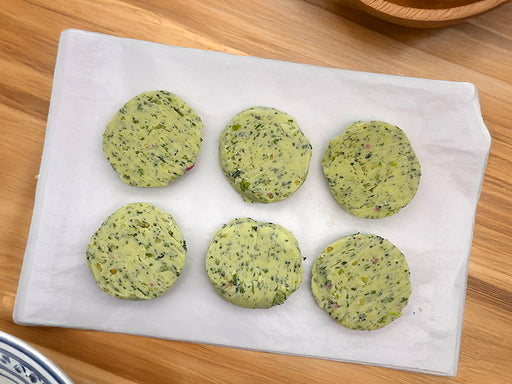 Fulton Fish Market Garlic & Herb Finishing Butter  - 6ct Pucks on white paper on wooden table surface