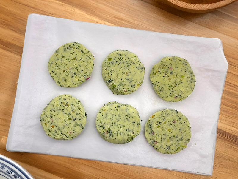 Fulton Fish Market Garlic & Herb Finishing Butter  - 6ct Pucks on white paper on wooden table surface