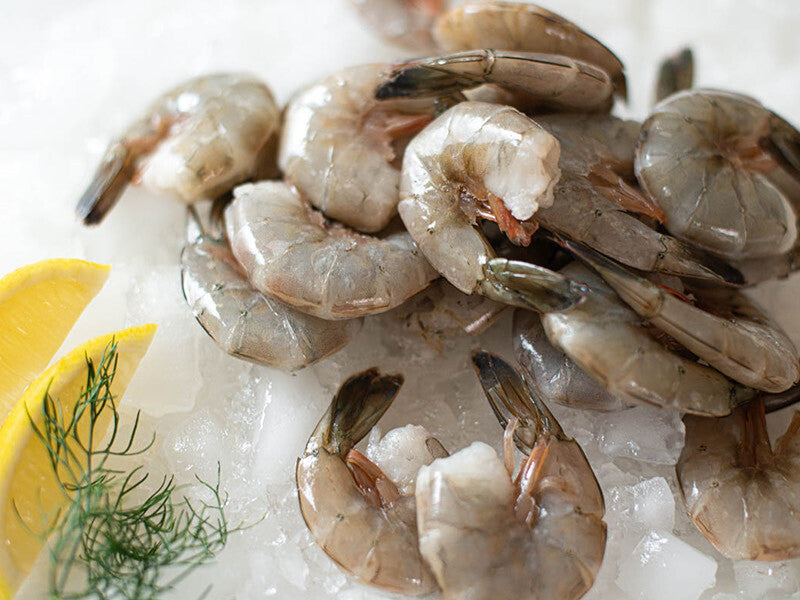 Close Up of Wild Colossal Blue Shrimp on Ice with Lemons and Herbs