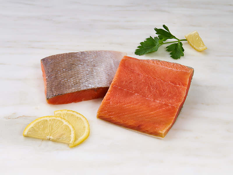 Wild Alaska Sockeye Salmon Portions on Marble Surface with Lemons and Parsley