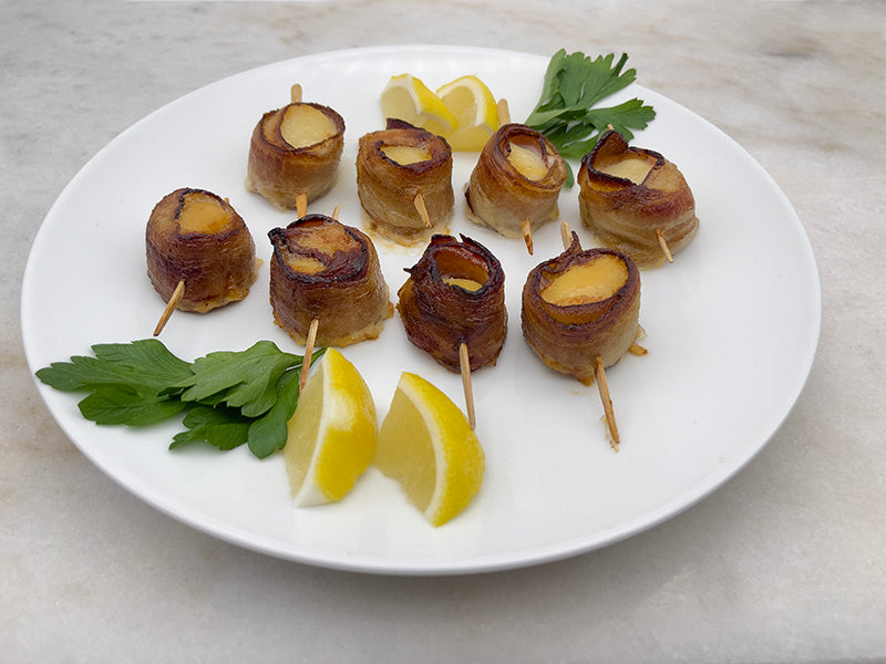 Bacon wrapped scallops cooked on plate with lemon and herrbs