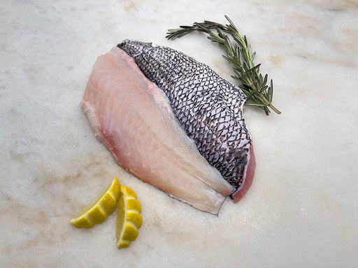 Wild Black Sea Bass portion on marble with herbs and lemon