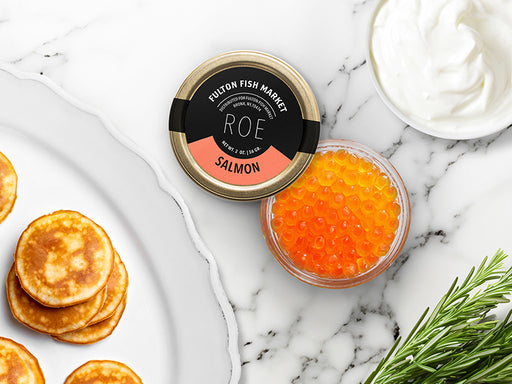 Salmon Roe Jar Opened on Marble Surface with Creme Fraiche and Blinis