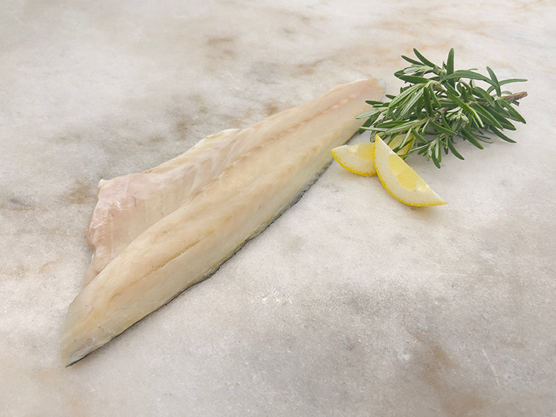 Branzino Fillet on marble with lemon and herbs