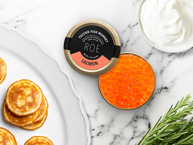 Fulton Fish Market Wild Salmon Roe Tin on Marble Surface with Creme Fraiche and Blinis