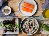 Salmon Portions, Shrimp, and Lobster Tails on Plates next to Olive Oil, Herbs, and Spices