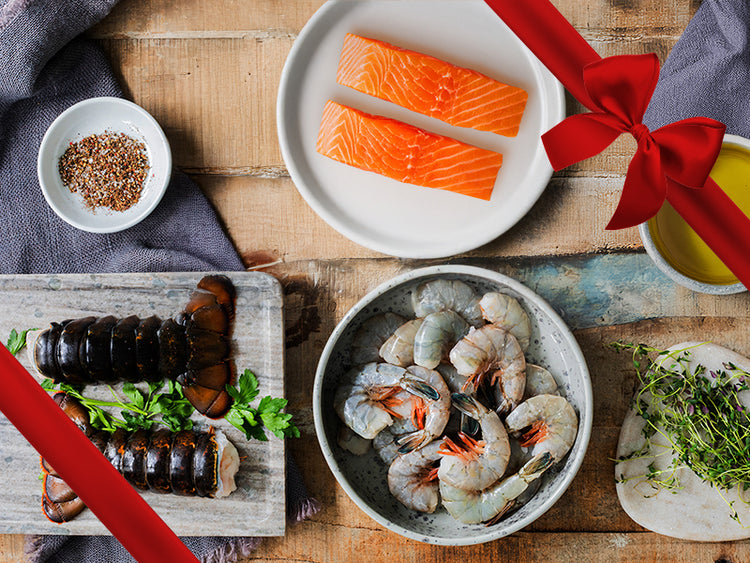 Atlantic Salmon, Shrimp, and Lobster Tails on Plates with Seasonings and Herbs with Gift Ribbon