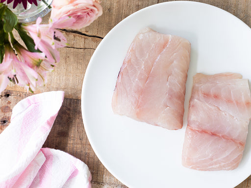 American Red Snapper Portions on Plate on Wood Table with Napkin and Flowers in Vase