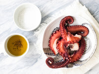 Cooked Octopus Tenatcles on Plate With Small Bowls of Olive Oil and Salt