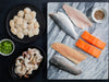 Sea Scallops and Wild Blue Shrimp on Plates and Atlantic Salmon Portions, Rainbow Trout Fillets, and Branzino Fillets on Marble Tray.