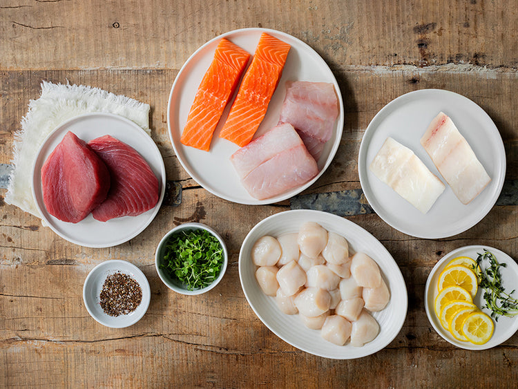 Sushi Bundle with Tuna, Salmon, Halibut, Red Snapper & Scallops with lemon and herbs on a wooden table