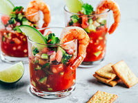 Fulton Fish Market Shellfish Hot Sauce with shrimp and limes in glasses and crackers