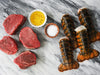 Four Filet Mignon Steaks and Two Lobster Tails on Marble Surface with Olive Oil and Salt
