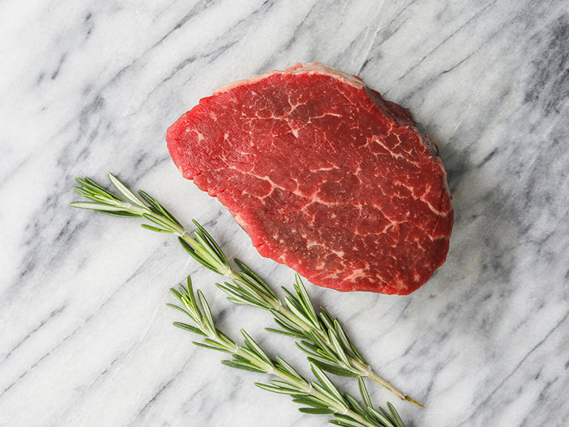 Raw Pat LaFrieda Prime Filet Mignon on Marble Surface with Rosemary Sprigs