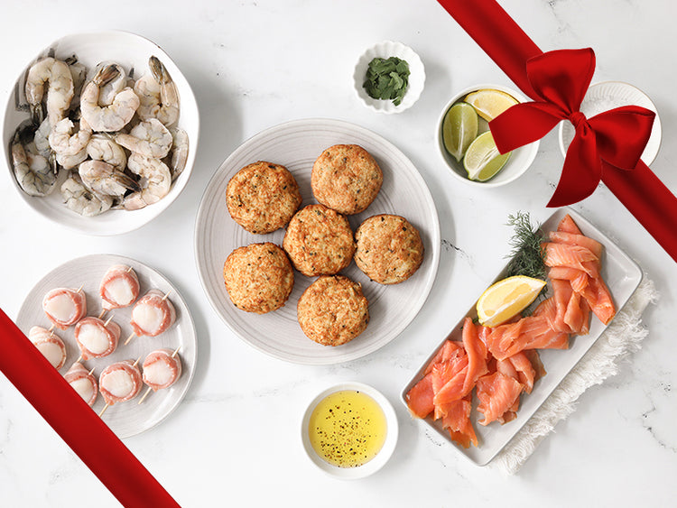 Bacon-Wrapped Scallops, Shrimp, Smoked Salmon, and Crab Cakes on Plates on Table with Gift Bow Graphic