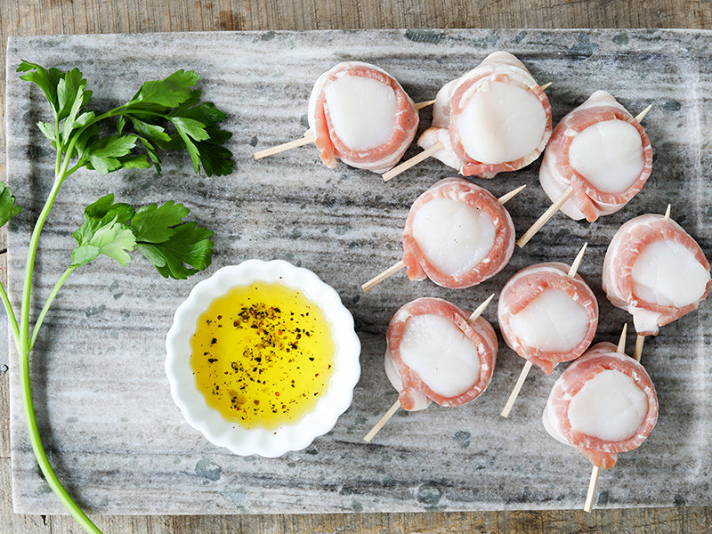 Bacon-Wrapped Scallops on Marble Tray with Olive Oil and Parsley