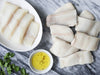 Wild Alaska Pacific Halibut and Wild Alaska Black Cod Portions on Marble Surface with Parsley and Olive Oil