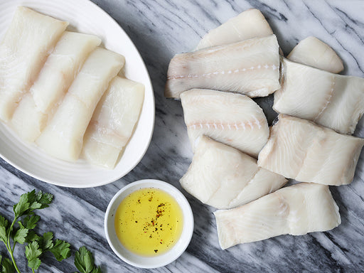 Wild Alaska Pacific Halibut and Wild Alaska Black Cod Portions on Marble Surface with Parsley and Olive Oil