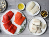 Wild Alaska Sockeye and Coho Salmon Portions, Wild Alaska Pacific Halibut Portions, and Wild Alaska Black Cod Portions on Plates on Wood Table
