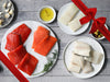 Wild Alaska Copper River Sockeye Salmon, Coho Salmon, Pacific Halibut, and Black Cod Portions on Plates on Wood Table with Gift Bow Graphic