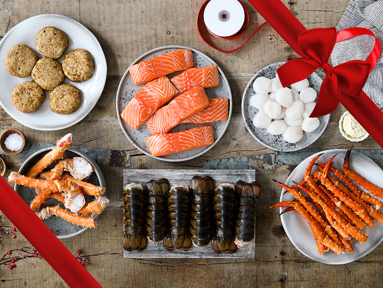 Scallops, Crab Cakes, Crab Legs, Lobster Tails, and Atlantic Salmon Portions on Plates on Wood Table with Gift Bow Graphic