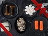 Lobster Tails, Scallops, Shrimp, Halibut, and Salmon on Plates on Dark Marble Table with Gift Ribbon