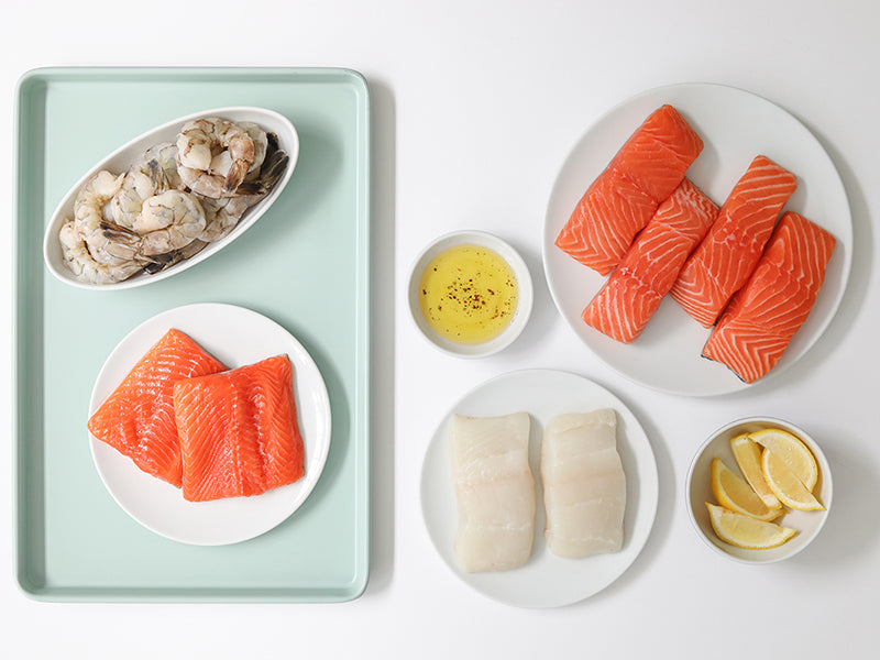 Atlantic Salmon Portions, Arctic Char Portions, Atlantic Halibut Portions, and Shrimp on Plates on Light Background