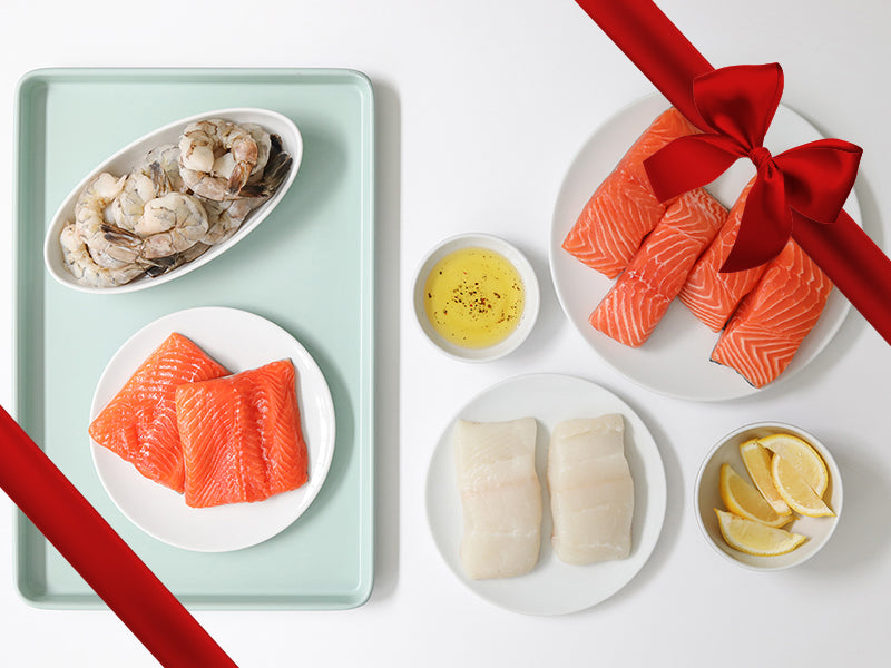 Arctic Char, Atlantic Halibut, Atlantic Salmon, and Shrimp on Plates with Lemon and Seasonings with Gift Ribbon