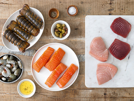 Atlantic Salmon Portions, Ahi Tuna Steaks, Swordfish Steaks, Shrimp, and Lobster Tails on Wood Table