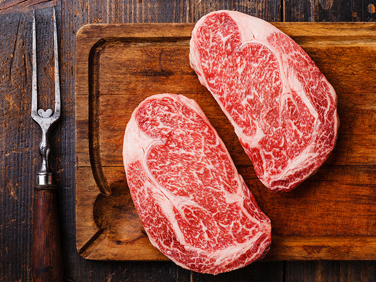 Raw Japanese A5 Wagyu Ribeye on Wood Cutting Board with cooking fork