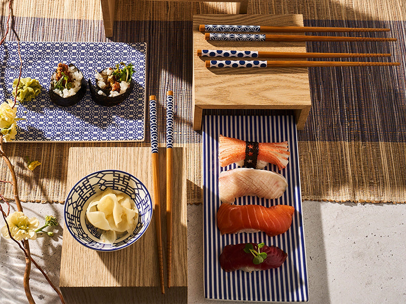 Sushi Tray with Nigiri next to chopsticks and a bowl of ginger