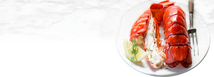 Cooked Lobster Tails on White Platter with Lemon Wedges