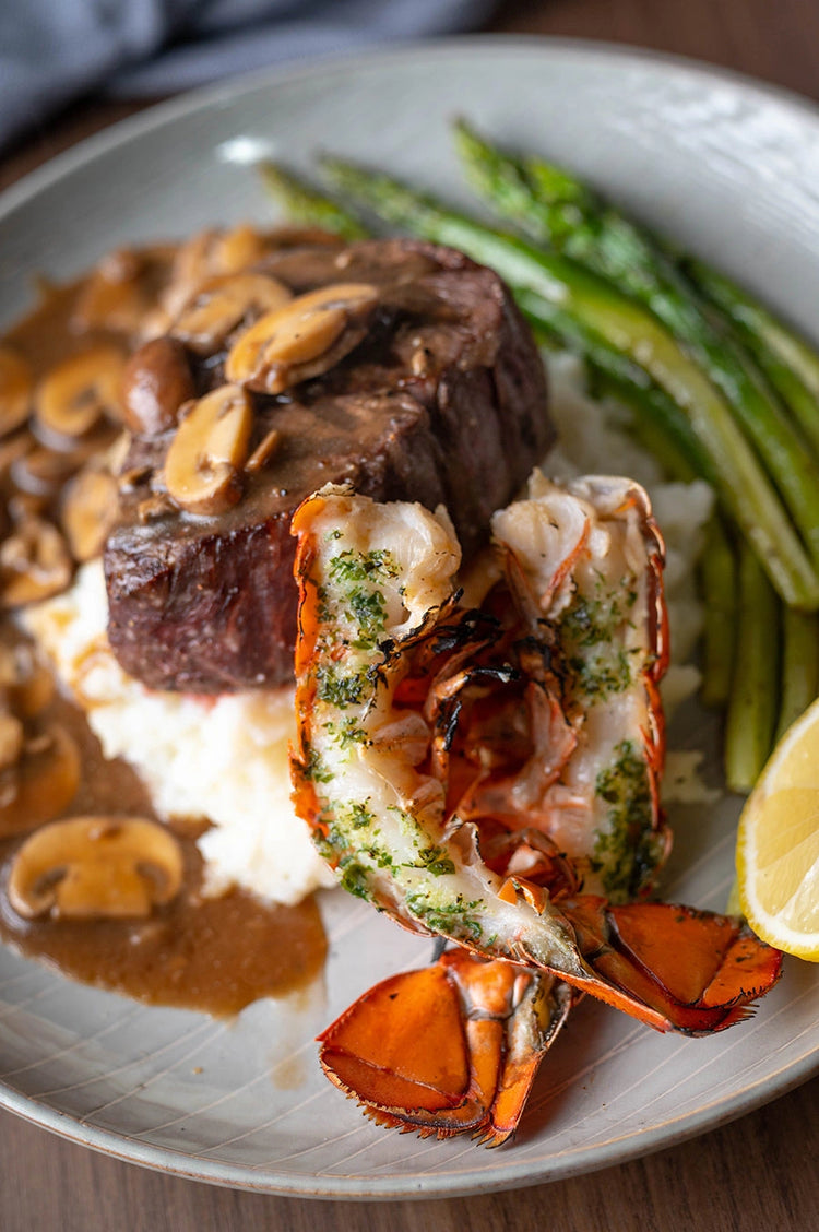 Surf and Turf Baked Lobster Tails with Steak on plate with asparagus