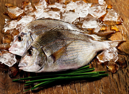 Whole Porgy on Wooden Surface with Ice and Chives