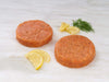 Atlantic Salmon Burger Patties on Marble Surface with Lemon and Herbs