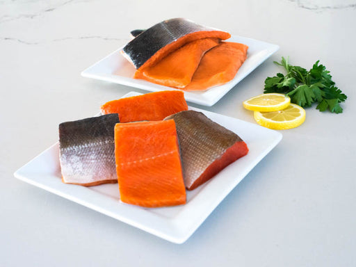Wild Alaska Sockeye Salmon & Coho Salmon Portions on Plates with Lemons and Herbs