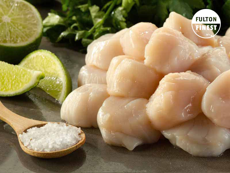 Dry Sea Scallops with Salt on Small Wooden Spoon and Lime Wedges